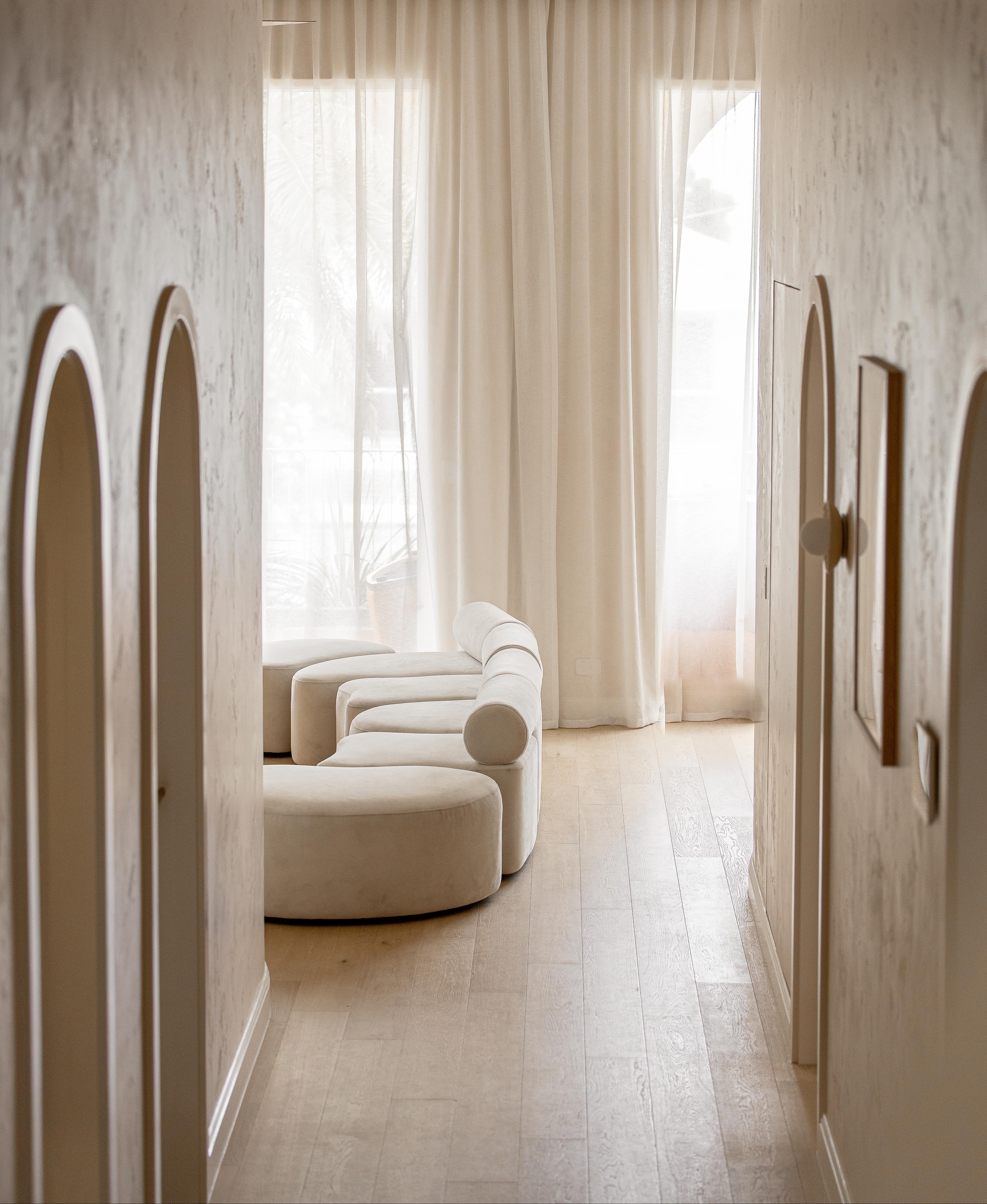 Modern interior with a curved Zulu cream sofa and light wood flooring.